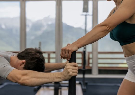 A couple working out together at an indoor gym with mountain views.