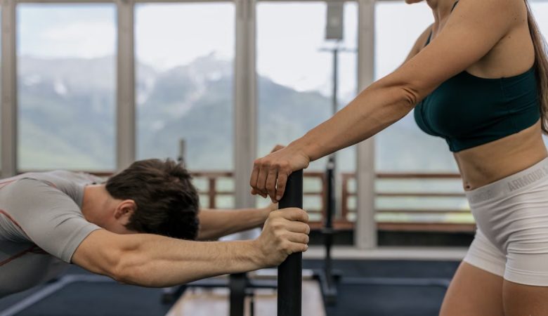 A couple working out together at an indoor gym with mountain views.